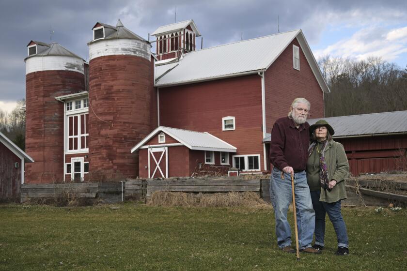 Joan and Harold Koster pose for a photo in front of a historic barn on their property, known as Itaska Valley Farm, Wednesday, March 13, 2024, in Whitney Point, N.Y. The Kosters were asked by Texas-based Southern Tier Energy Solutions to lease their land to extract natural gas by injecting carbon dioxide into the ground, which they rejected and are opposed to. (AP Photo/Heather Ainsworth)