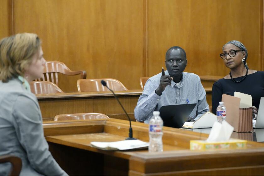 Lisa Ross, right, attorney for Bul Mabil, seated center, brother of Dau Mabil, a 33-year-old Jackson, Miss., resident who went missing on March 25 and whose body was found in April floating in the Pearl River in Lawrence County, listens to his question, while Karissa Bowley, wife of the deceased, awaits a renewed spate of questions during a hearing, on whether a judge should dissolve or modify his injunction preventing the release of Mabil's remains until an independent autopsy could be conducted, Tuesday, April 30, 2024, in Jackson, Miss. (AP Photo/Rogelio V. Solis)
