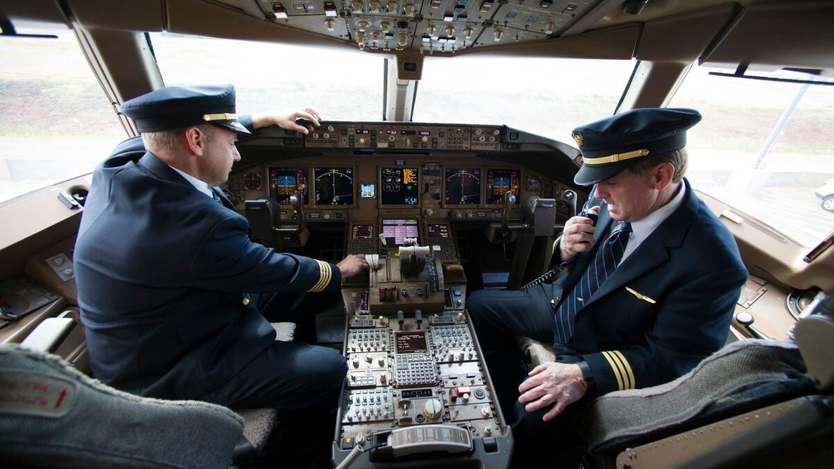United Airlines Capt. Tommy Holloman, left, and Capt. Chuck Stewart demonstrate the radio from the cockpit of a Boeing 777.