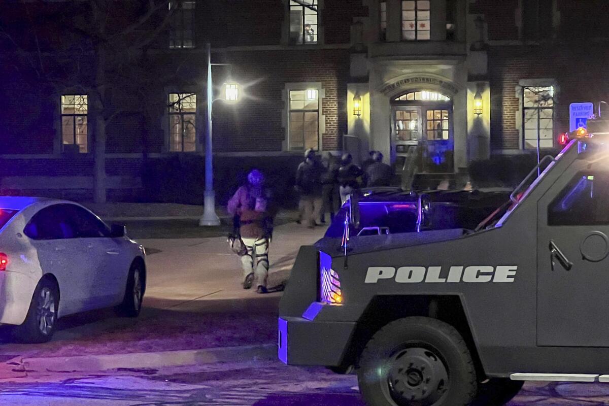 Armed police officers with weapons drawn rush into Phillips Hall on the campus of Michigan State University