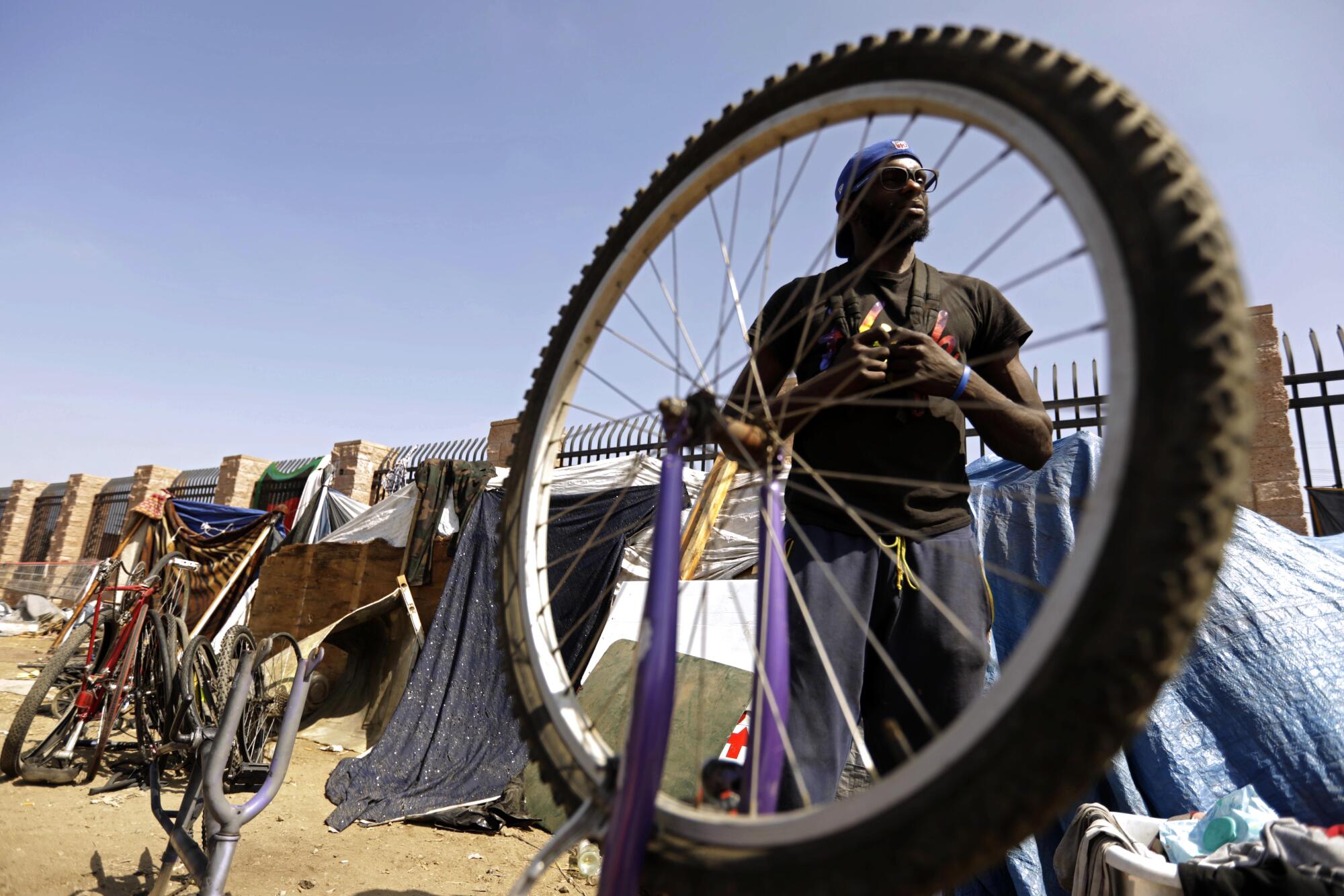 Desmond Perkins, who is homeless, prepares to work on bikes he stores in a section of a 10-acre vacant lot in Watts.