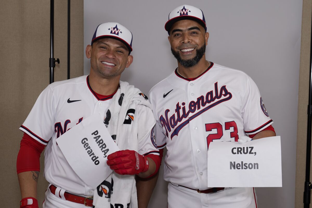 Washington Nationals Gerarado Parra, left, and Nelson Cruz, right, smile after arriving at the same time for a portrait session at baseball spring training Thursday, March 17, 2022, in West Palm Beach, Fla. (AP Photo/Sue Ogrocki)