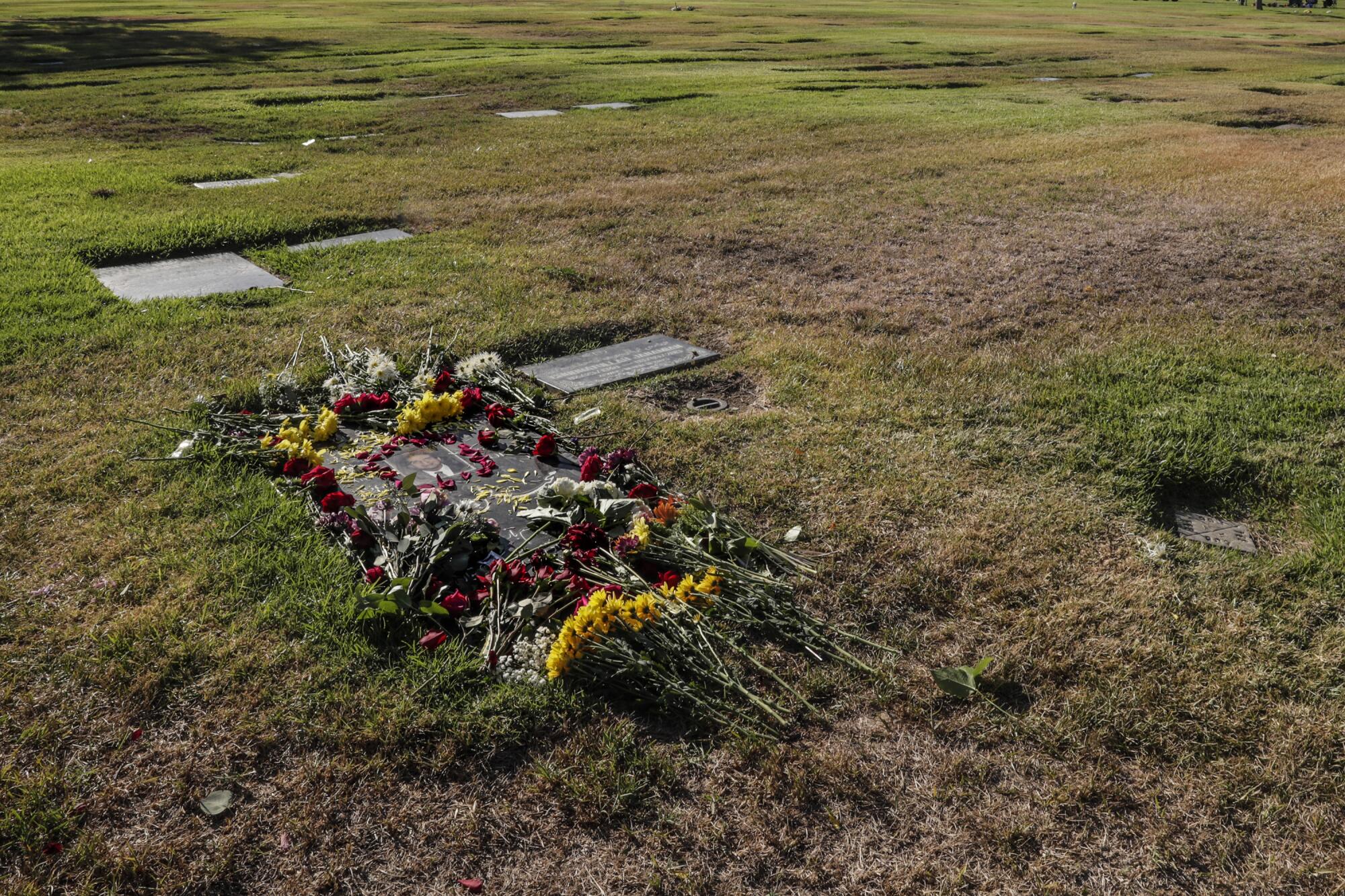 Flowers are arranged on a gravestone in the grass