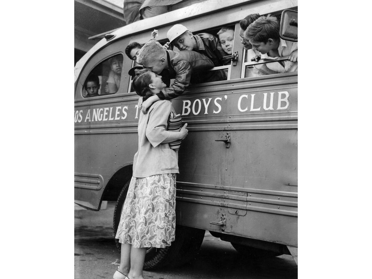 July 6, 1955: Albert Fathergill, 9, leans from bus to kiss mother Mrs. Ethel Fathergill, as 19 members of the Times Boys Club leave for summer camp.