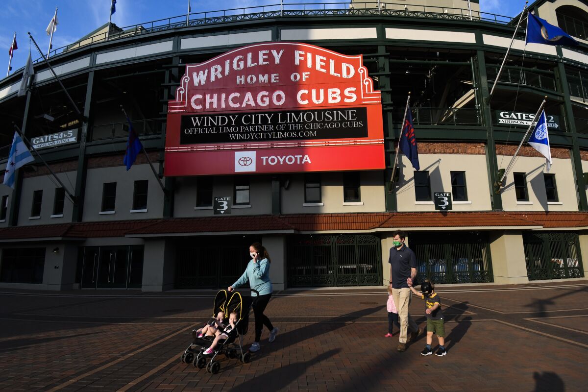 FILE - People wear face masks and walk outside Wrigley Field in Chicago, Ill., before a baseball game between the Chicago Cubs and the Minnesota Twins on Sunday, Sept. 20, 2020. The federal government sued the Chicago Cubs on Thursday, July 14, 2022, and accused the team of failing to make Wrigley Field accessible to those with disabilities when the century-old ballpark was modernized to add luxury seating, bathrooms and restaurants. (AP Photo/Matt Marton, File)