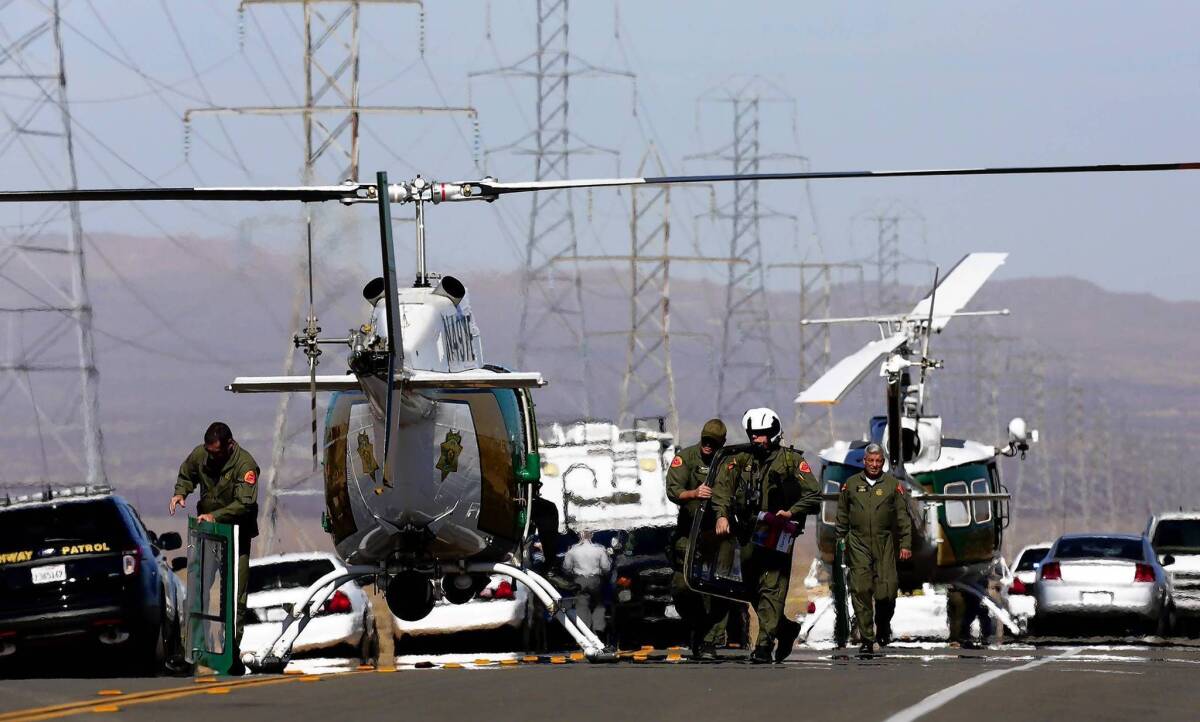 Helicopters and police vehicles block U.S. 395 in Central California south of Ridgecrest where officers killed a gunman after an hourlong chase. Two wounded people were found in the trunk of the fleeing car.