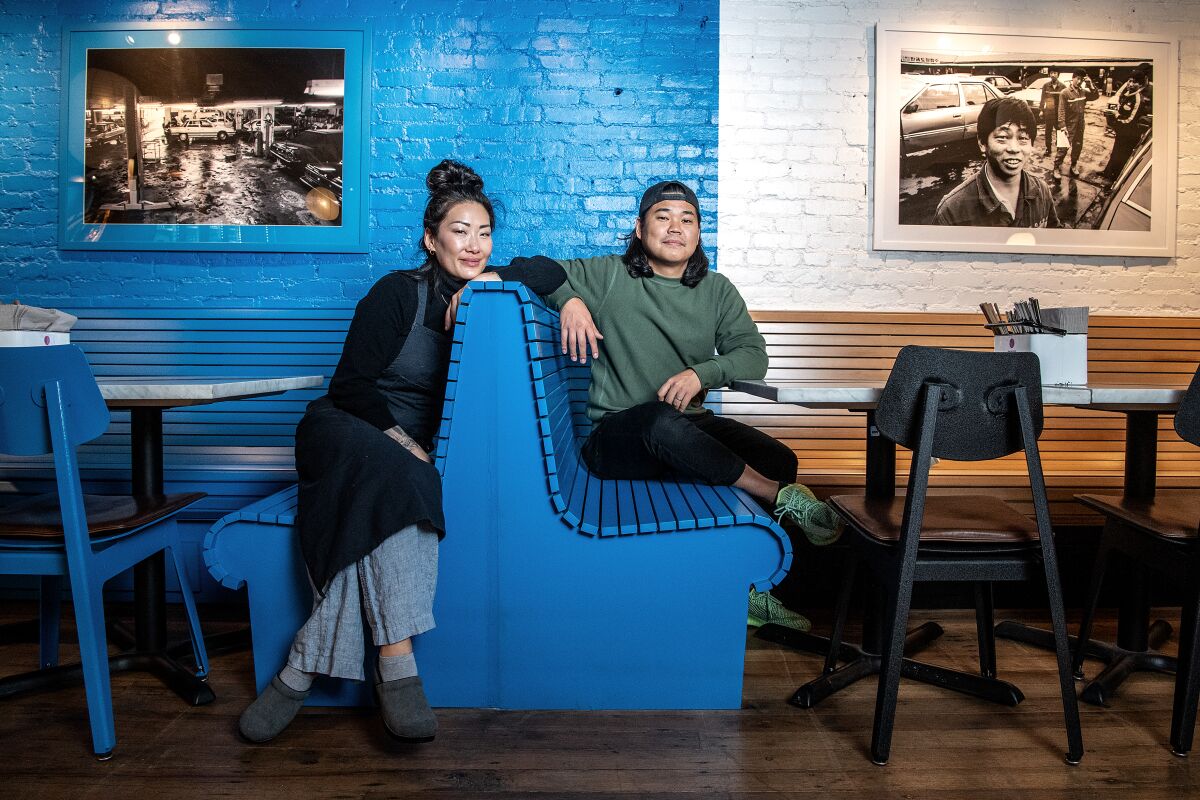 Two restaurateurs sit in booths at their restaurant.