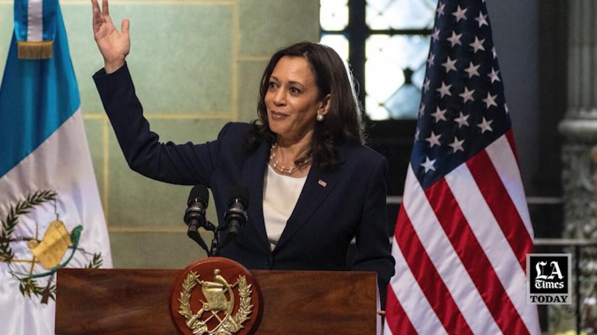 Vice President Kamala Harris waves from behind a lectern.