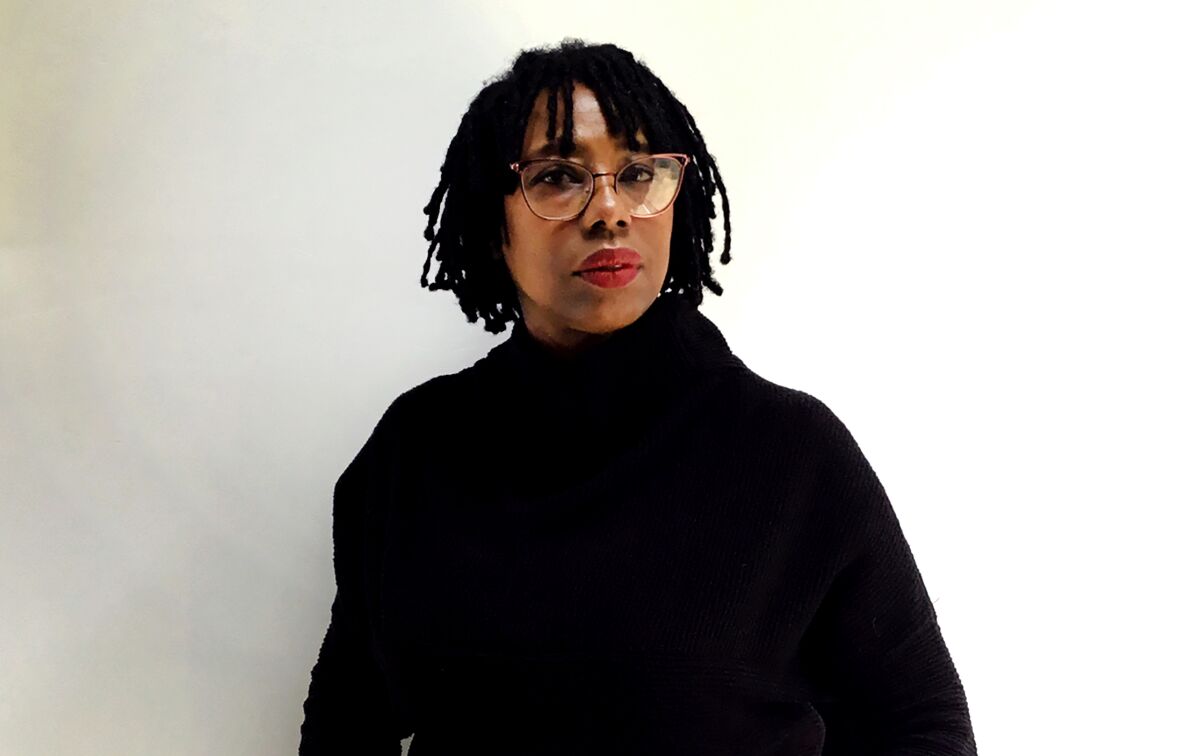 A Black woman in a black turtleneck and glasses 