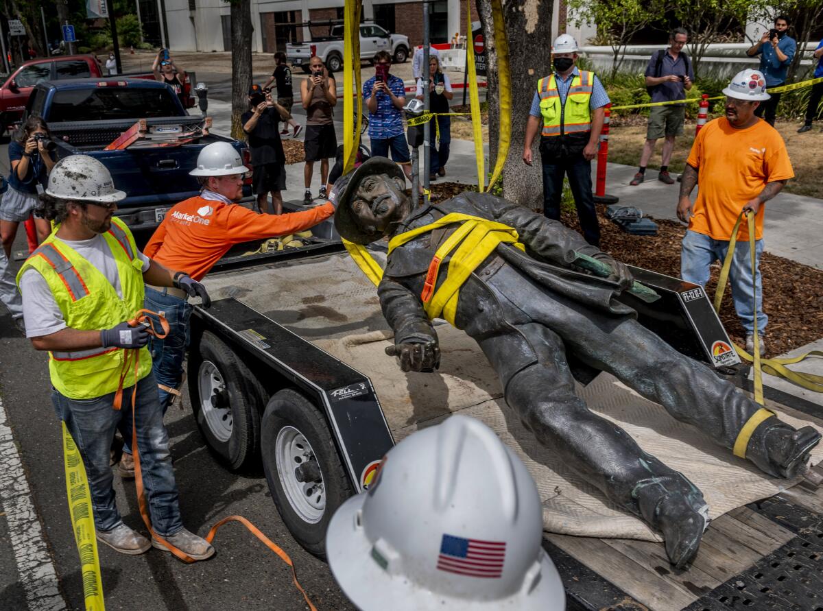 Workers remove a statue of John Sutter from a Sacramento hospital on Monday.