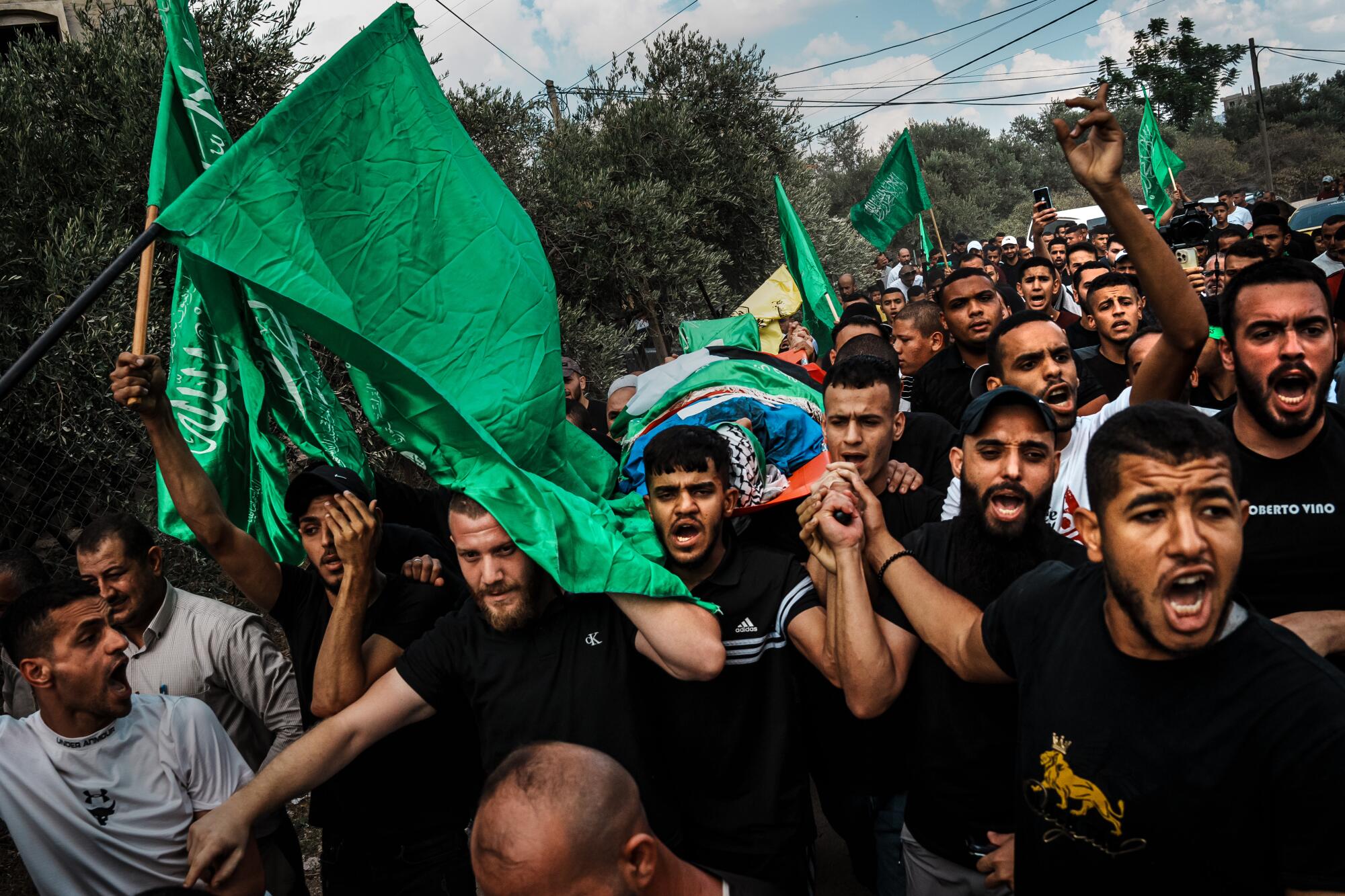 Mourners surround and march carrying Ali Khazneh to his burial.
