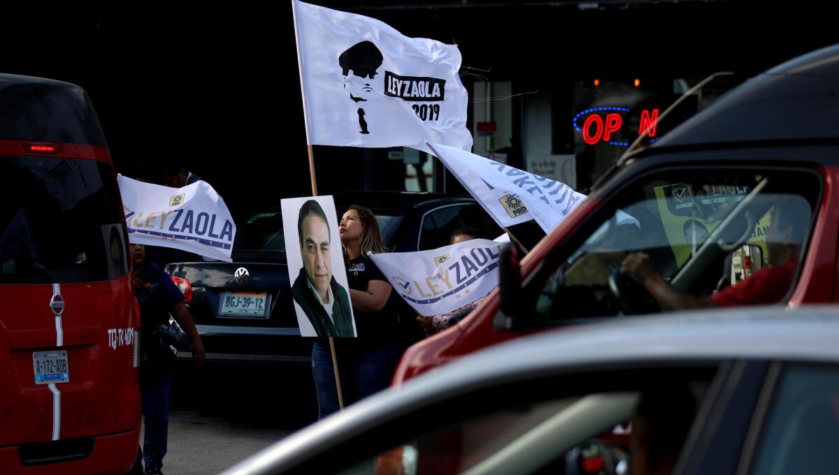 Los partidarios ondean banderas en apoyo a Julian Leyzaola, el candidato a alcalde del Partido de la Revolución Democrática en Tijuana, mientras asiste a un foro de negocios en la ciudad. (Gary Coronado / Los Angeles Times)