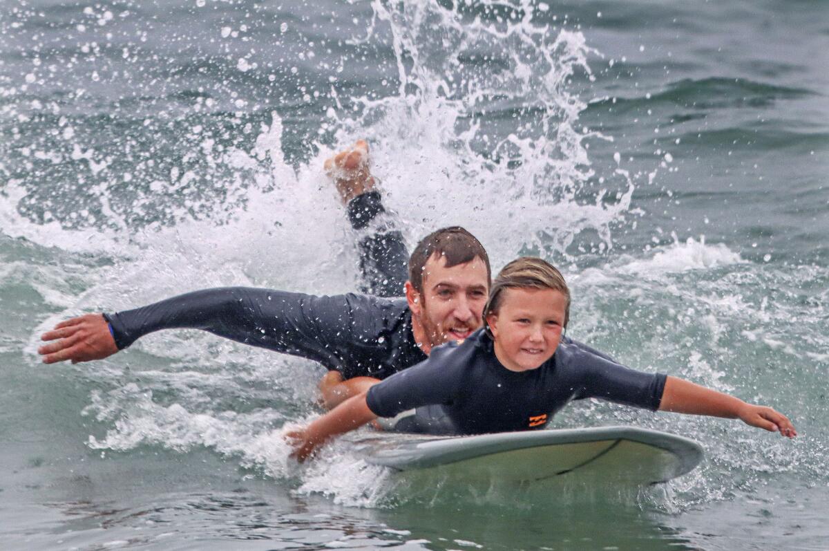 Hayden Lane helps his nephew Fisher Lane, 8, catch a wave during the 14th Annual B2M  Wave Challenge.