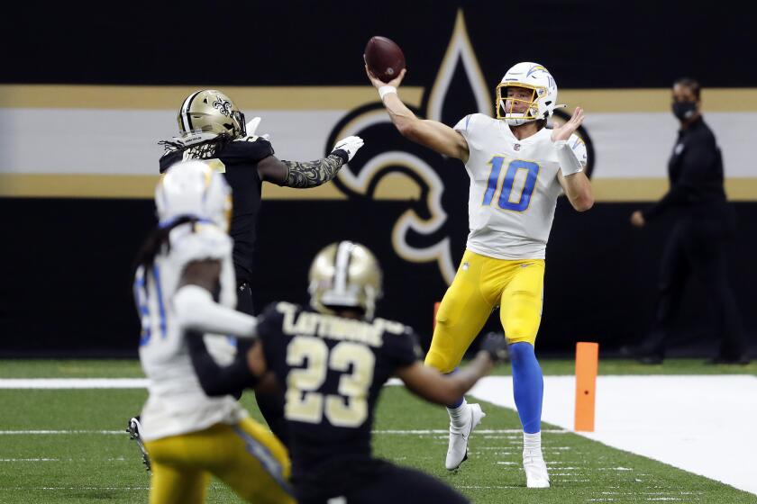 Los Angeles Chargers quarterback Justin Herbert (10) throws the ball in front of New Orleans Saints outside linebacker Demario Davis (56) during an NFL football game, Monday, Oct. 12, 2020, in New Orleans. (AP Photo/Tyler Kaufman)