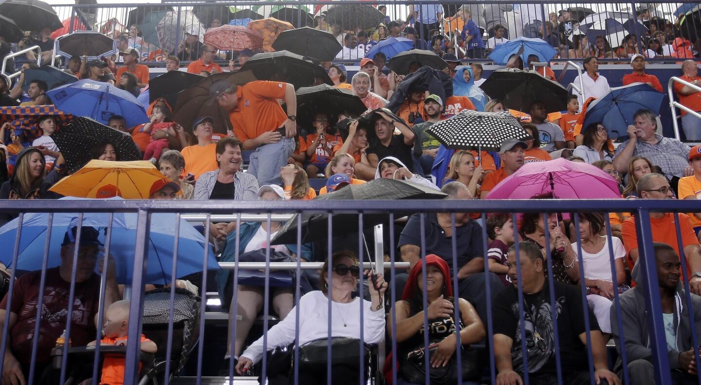 Fans shield themselves from rain during a lightning delay at the Bishop Gorman-St. John Bosco game.
