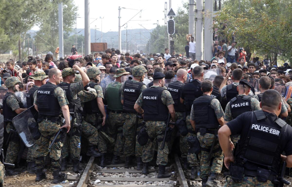 Macedonian police officers block migrants from entering Macedonia illegally from Greece at the railway tracks on the border near Gevgelija on Aug. 21.