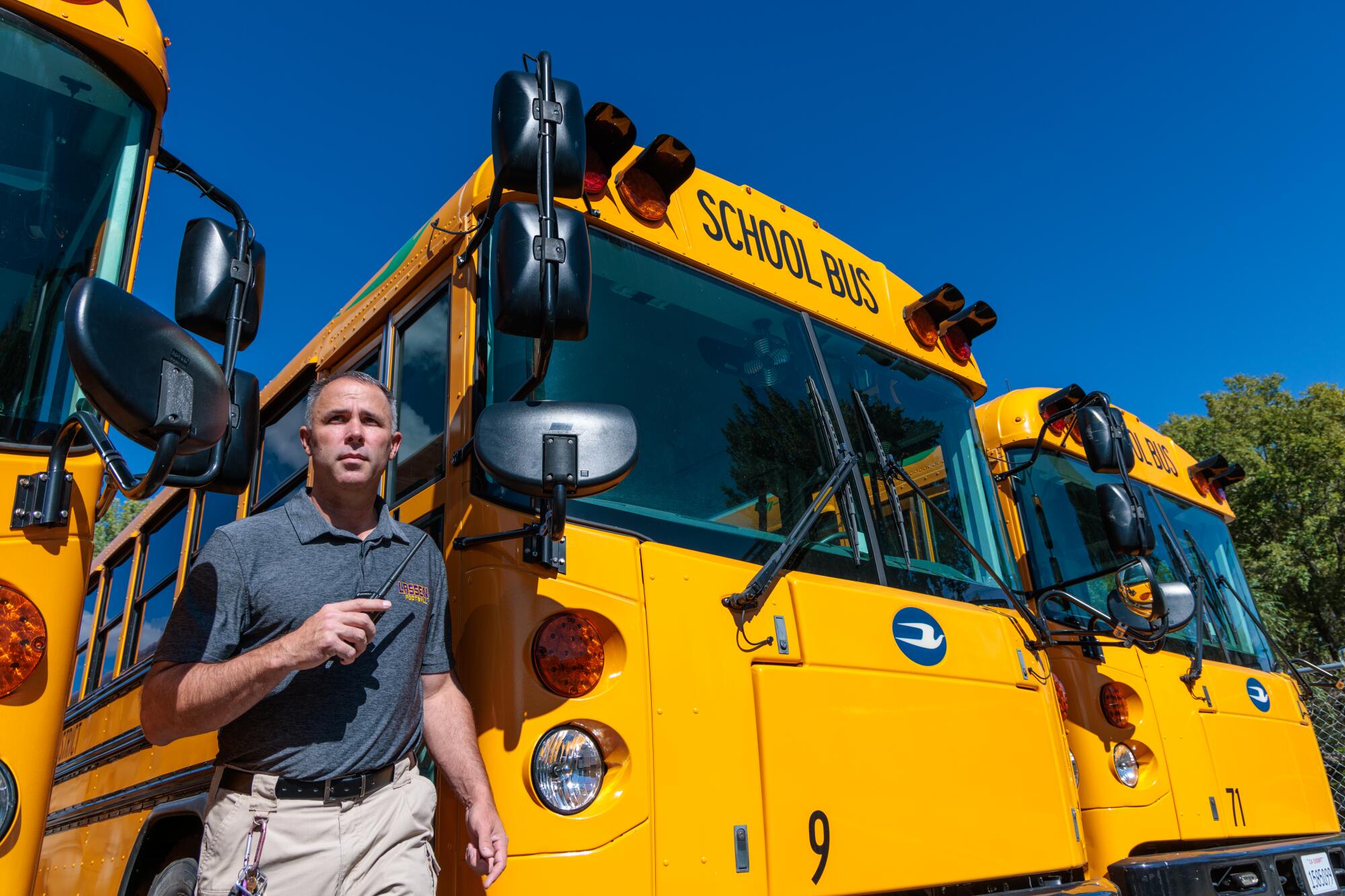A man stands near a row of parked school buses.