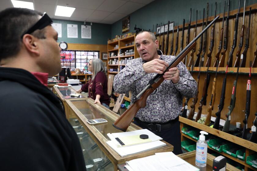 REDDING, CA - JANUARY 07: Patrick Jones, 52, right, of Redding, Shasta County Supervisor, District 4, helps a customer with the purchase of a 30-06 CZ hunting rifle at his business Jones' Fort gun shop on Thursday, Jan. 7, 2021 in Redding, CA. Newly elected Jones was one of two Shasta County Supervisors who unlocked the doors to the chambers to hold an in-person meeting in that was supposed to be virtual to protest statewide COVID-19 restrictions, in Redding. (Gary Coronado / Los Angeles Times)