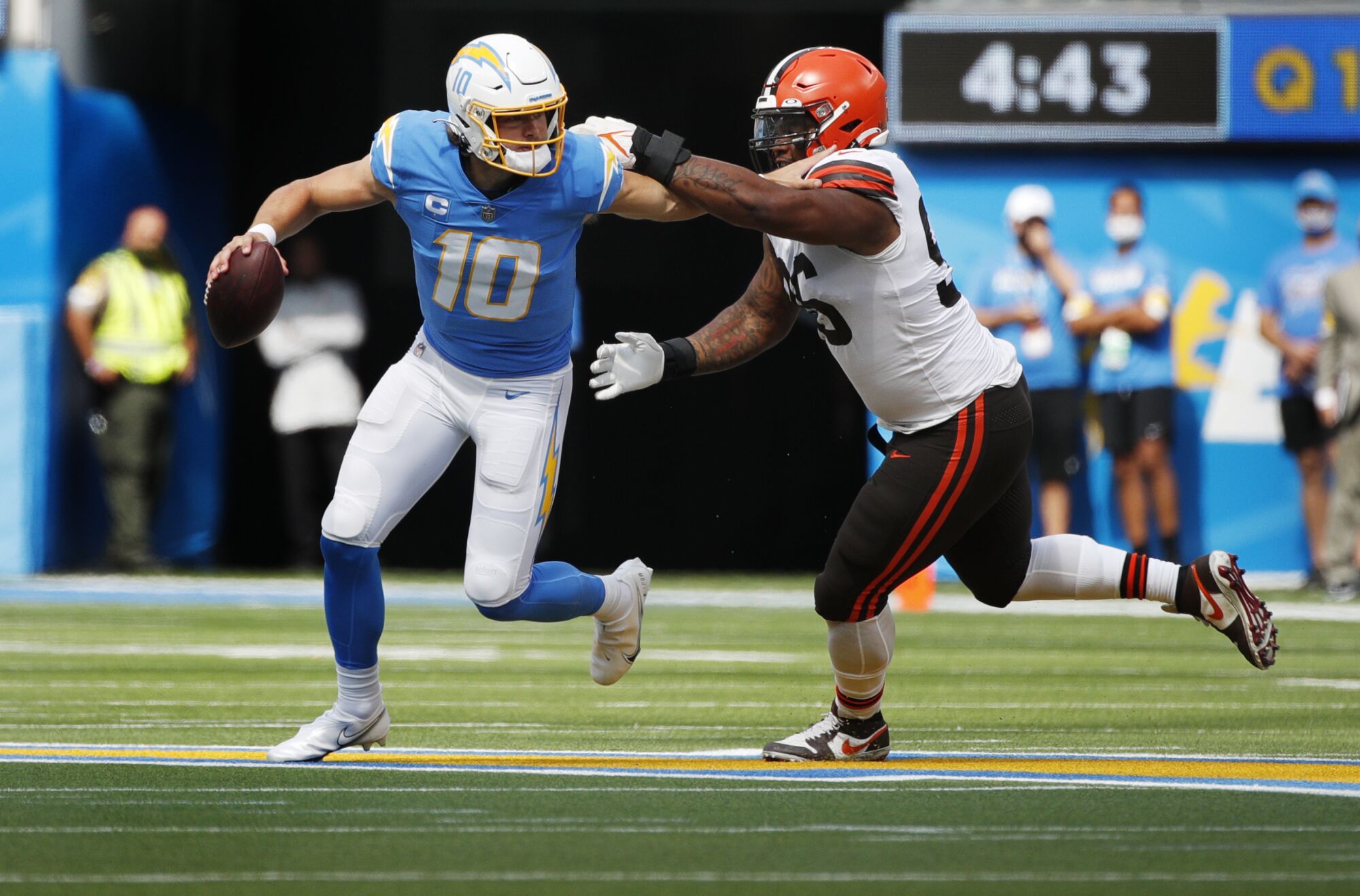 Chargers quarterback Justin Herbert, left, tries to evade Cleveland Browns defensive tackle Jordan Elliott.