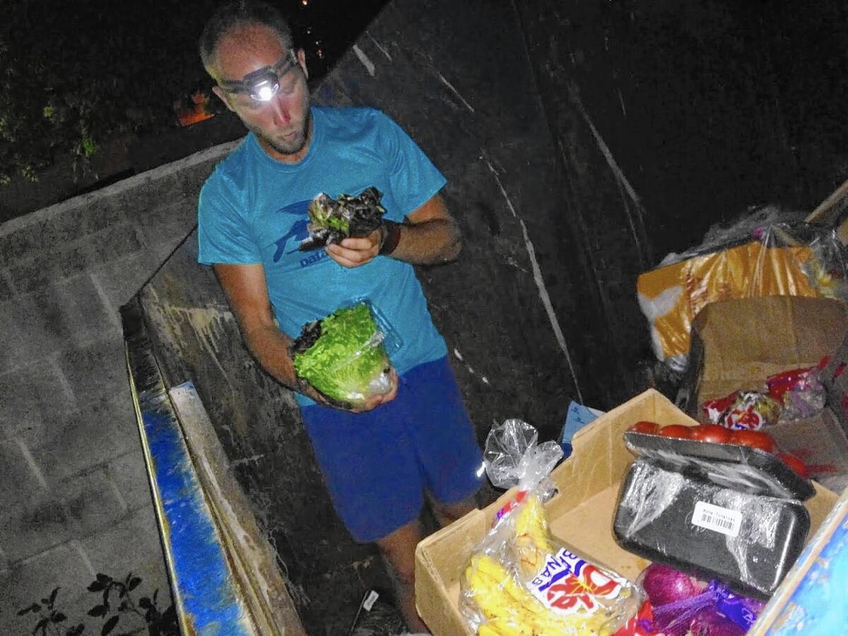 Activist Rob Greenfield inspects the contents of a dumpster near Cleveland, looking for food to put on display for the pubilc in an attempt to raise awareness about how much food is wasted every day.