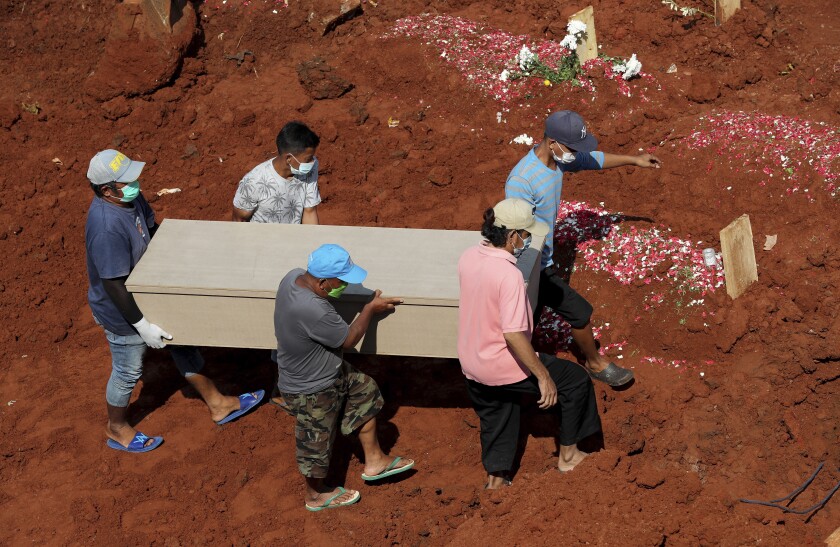 Workers carry a coffin for burial at the special section of Jombang Public Cemetery reserved for those who died of COVID-19, in Tangerang, on the outskirts of Jakarta, Indonesia, Wednesday, Aug. 4, 2021. Indonesia surpassed 100,000 confirmed COVID-19 deaths on Wednesday, a grim milestone in a country struggling with its worst pandemic wave fueled by the delta variant, amid concerns the actual figure could be much higher. (AP Photo/Tatan Syuflana)