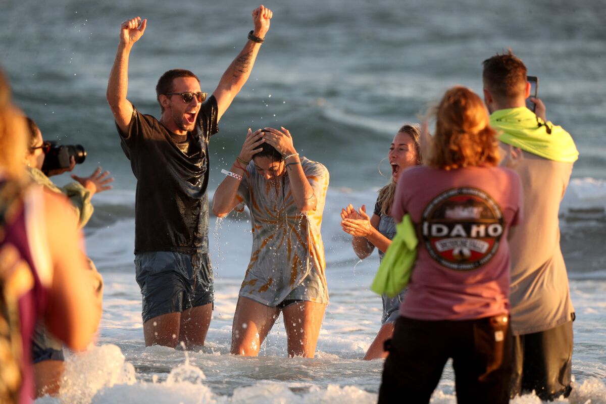 Alyssa Skobis, center, of Downey is baptized in the Pacific Ocean by Joe Ferguson and his wife Taylor Ferguson, right.