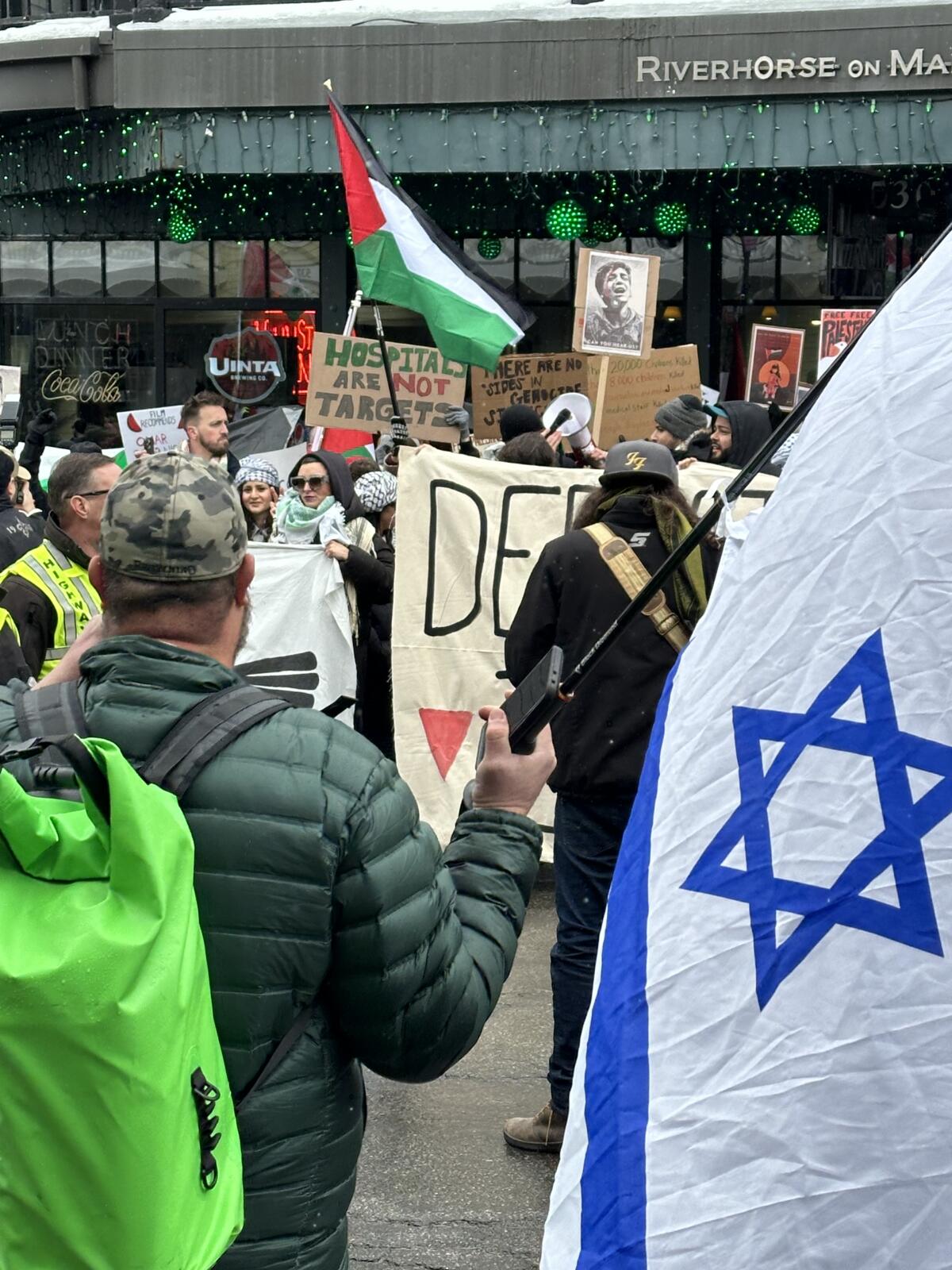A pro-Israel counter-protester carries an Israeli flag.
