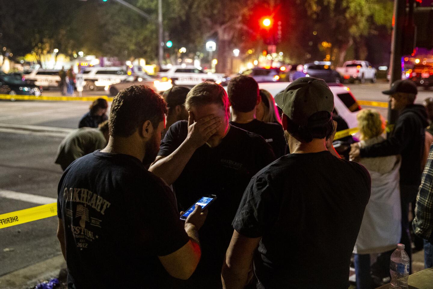People stand in a parking lot along South Moorpark Road in the aftermath of the shooting.