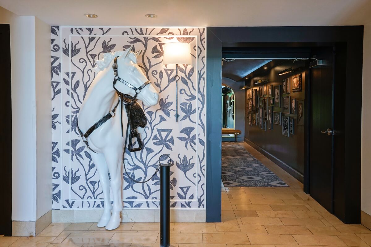 A sculpture of a horse appears to be emerging from a wall next to a hallway.