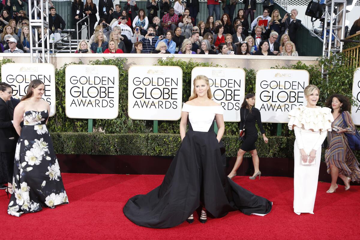 Comedian Amy Schumer walks the red carpet at the 73rd Golden Globe Awards at the Beverly Hilton Hotel on Sunday. At left is her sister and writing partner, Kim Caramele.