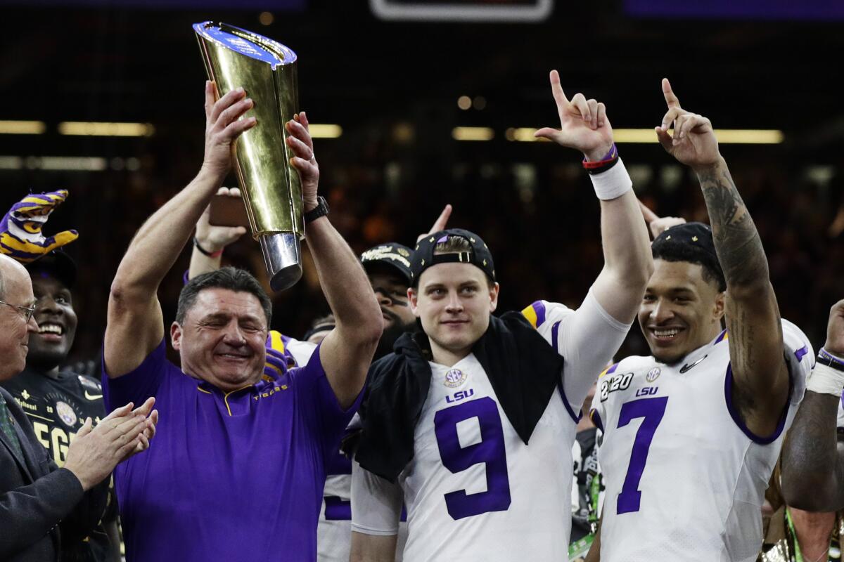 Louisiana State coach Ed Orgeron holds the trophy beside quarterback Joe Burrow, center, and safety Grant Delpit after beating Clemson in the College Football Playoff championship game on Monday in New Orleans.