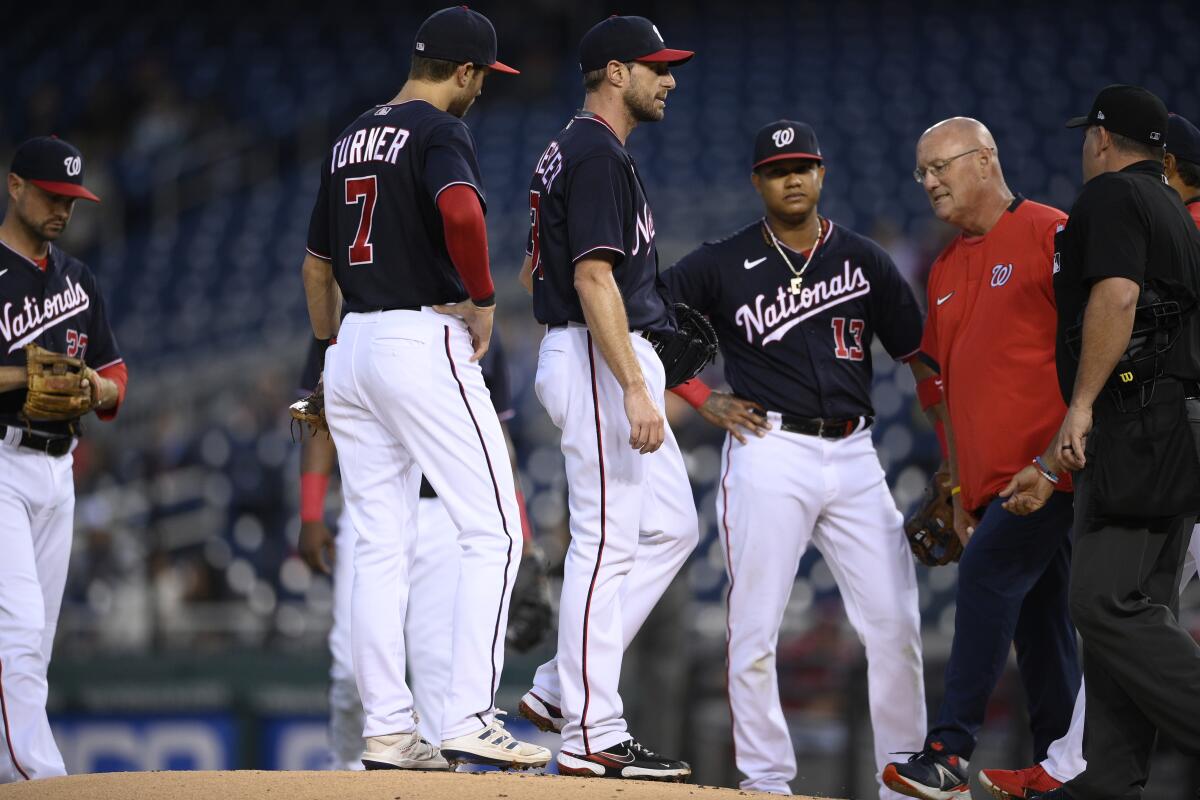 Nationals starting pitcher Max Scherzer, center, stands on the mound as a trainer comes to check on him June 11, 2021.
