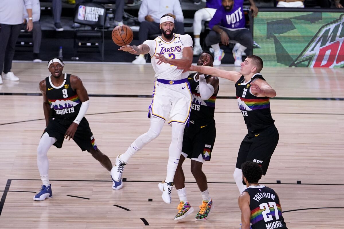 Lakers forward Anthony Davis makes a pass under pressure from Nuggets defenders during Game 3.