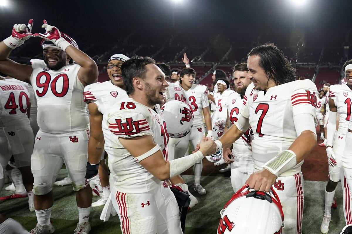 Utah quarterback Cameron Rising, right, and receiver Britain Covey (18) celebrate beating USC 