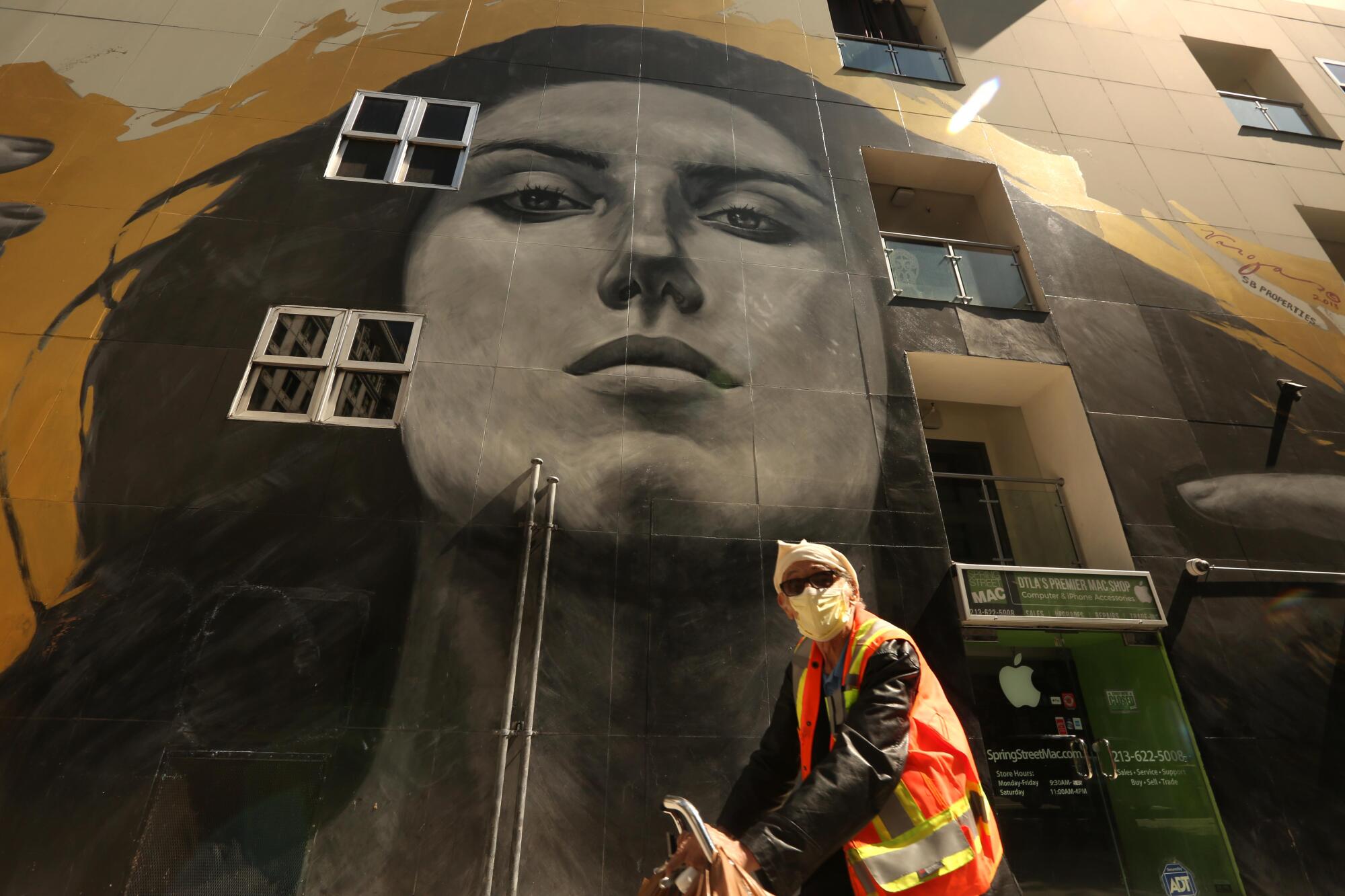 A bicyclist rides past a mural by street artist Robert Vargas in downtown Los Angeles.