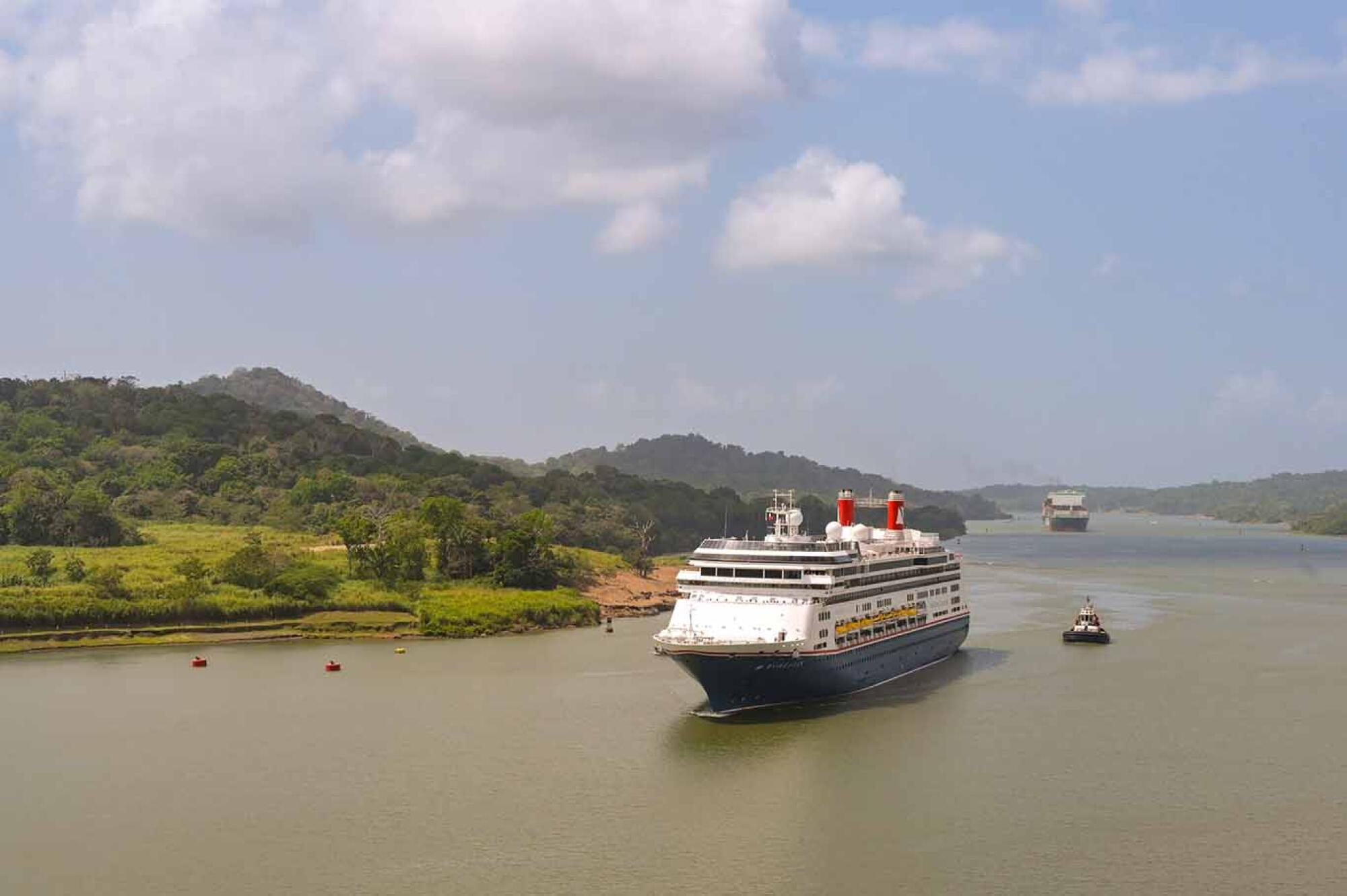 Cruise ship Borealis sailing the Panama Canal escorted by a tug boat.