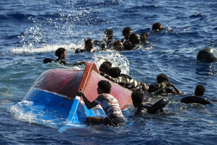 FILE - Migrants swim next to their overturned wooden boat during a rescue operation by Spanish NGO Open Arms at south of the Italian Lampedusa island at the Mediterranean sea, Aug. 11, 2022. European Union lawmakers approved on Thursday, April 20, 2023 a series of proposals aimed at ending the years-long standoff over how best to manage migration, a conundrum that has provoked one of the bloc's biggest political crises. (AP Photo/Francisco Seco, File)