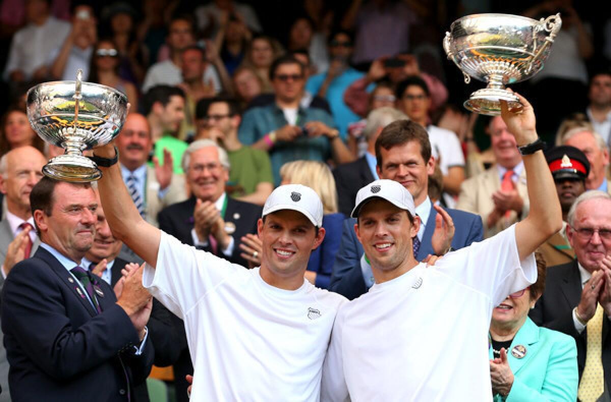Mike and Bob Bryan hold trophies aloft after winning the doubles title at Wimbledon on Saturday.
