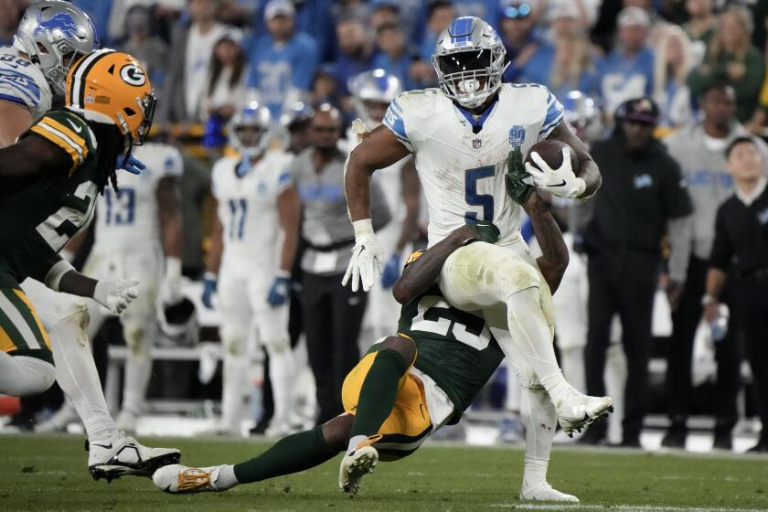 David Montgomery, corredor de los Lions de Detroit, resiste el intento de derribo por parte de Rasul Douglas, de los Packers de Green Bay, en el encuentro del jueves 28 de septiembre de 2023 (AP Foto/Morry Gash)