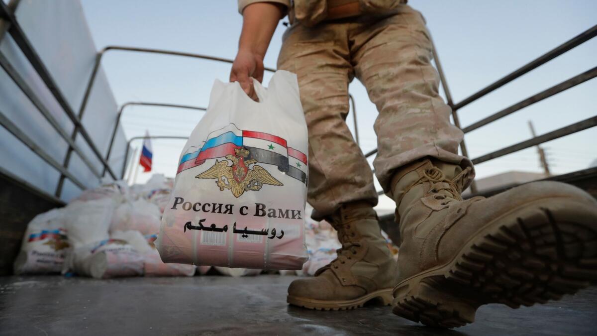A Russian officer prepares to distribute food aid for local residents in the outskirts of Damascus.