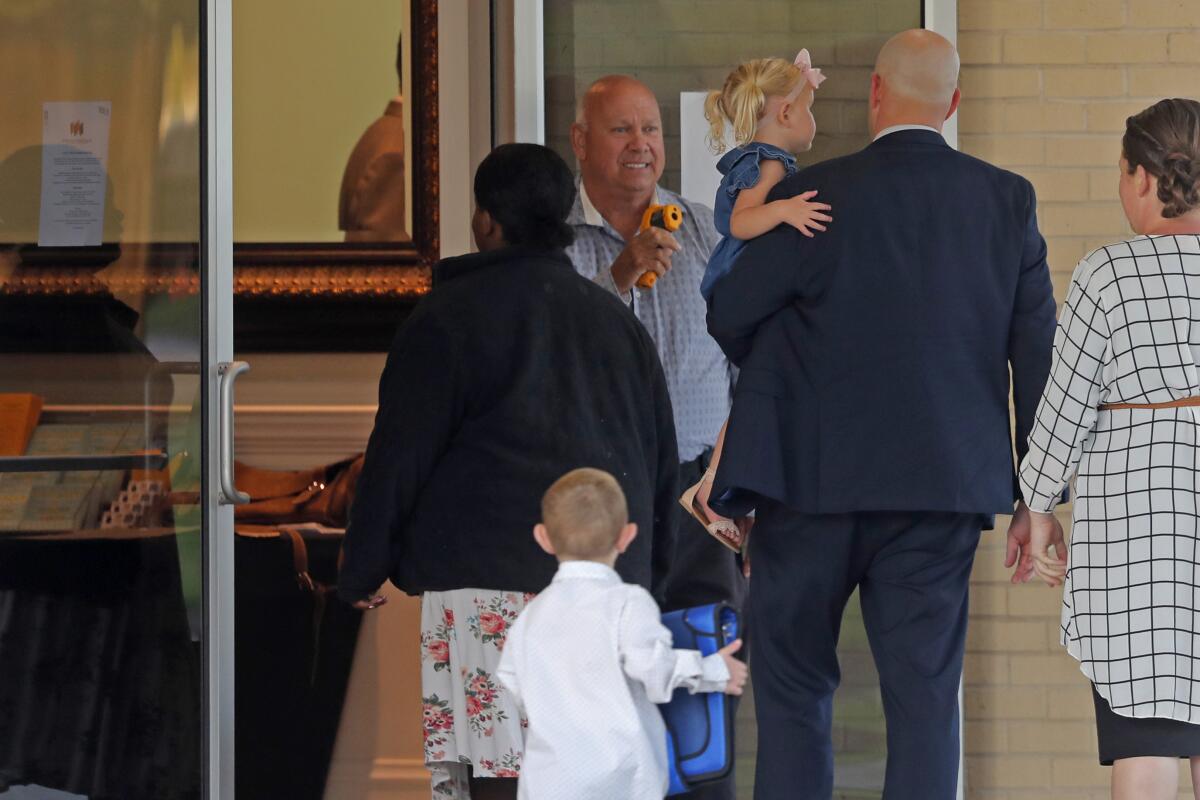 A man takes temperature scans as congregants arrive for evening service at the Life Tabernacle Church in Central, La., Tuesday, March 31, 2020. Pastor Tony Spell held services despite being charged with misdemeanors today, for holding services against Gov. John Bel Edwards shelter-in-place order due to the new coronavirus pandemic.