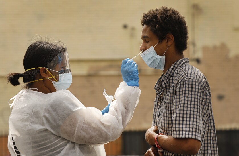 Nurse practitioner Shannon Fernando with Los Angeles Christian Health Centers takes a swab sample from Brian Wilson on skid row in Los Angeles.