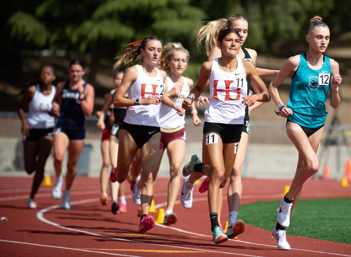 Huntington Beach's Sydney Rubio (11) and Makenzie McRae (2) compete in the 3,200-meter race at the CIF Masters Meet.