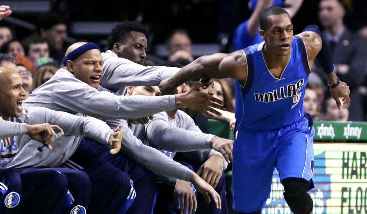Mavericks guard Rajon Rondo (9) is congratulated by teammates after hitting a three-pointer in front of the bench during the first quarter of their game against the Celtics in Boston on Friday.