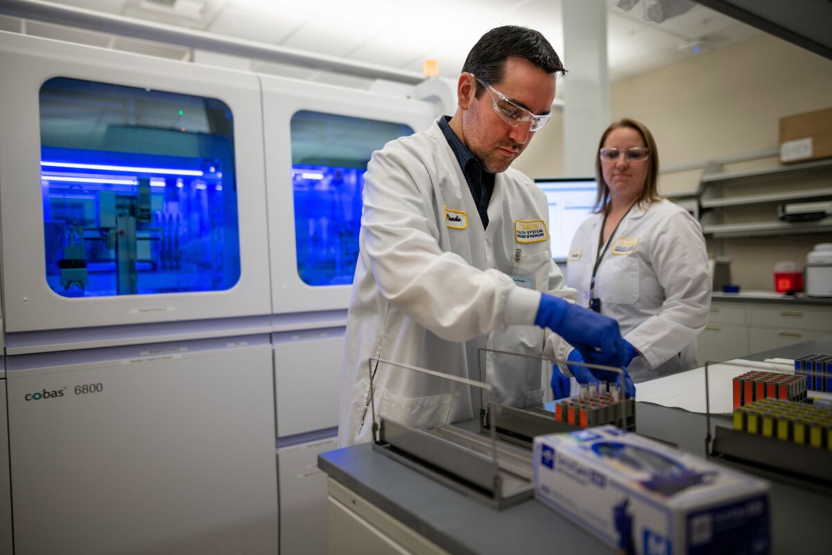 Marcelo Prado and Katie Zegarski, at UC Davis Health in Sacramento, demonstrate an instrument to be used for coronavirus testing.