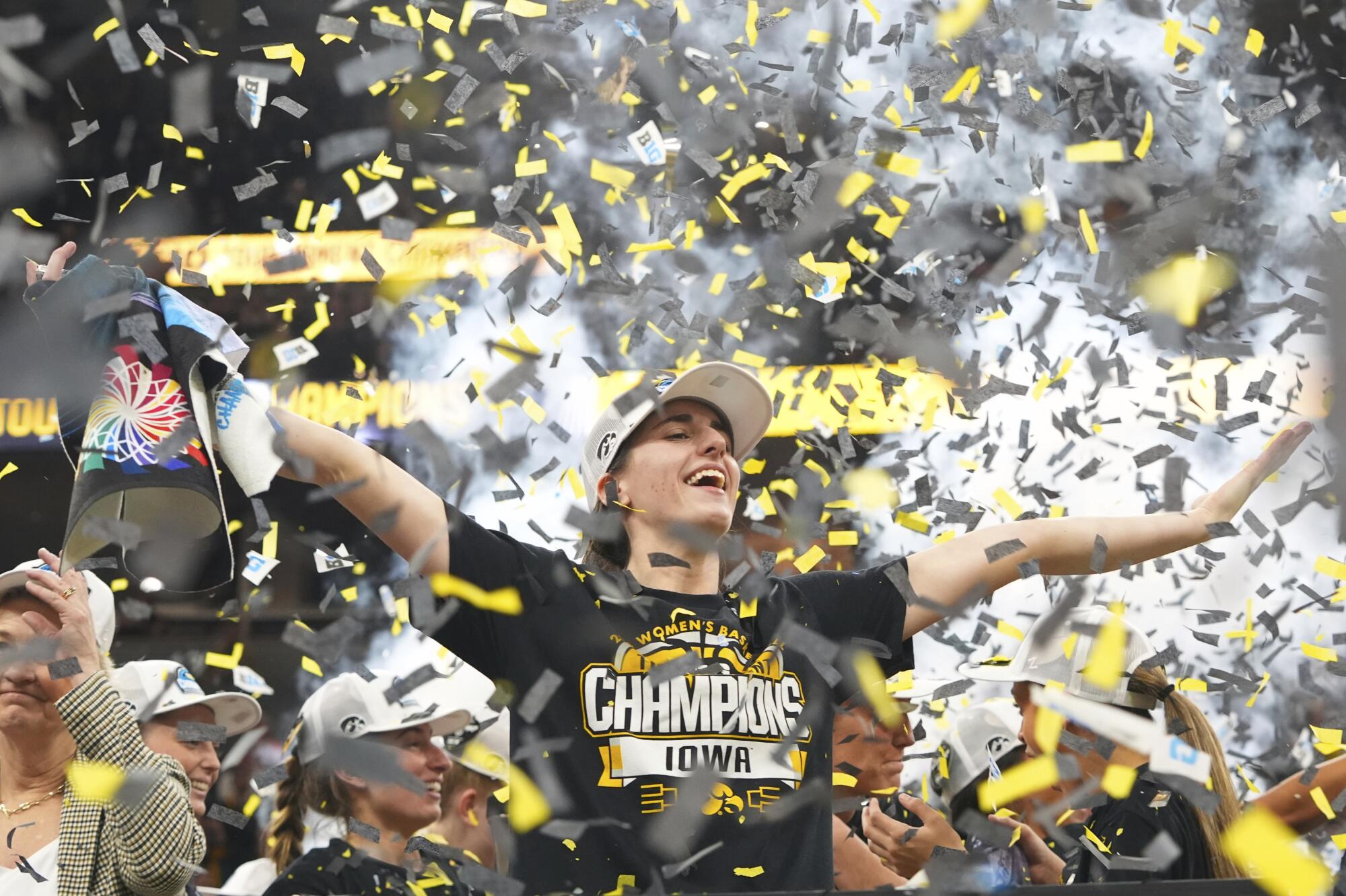 Iowa guard Caitlin Clark closes her eyes with her arms outstretched as confetti falls on the basketball court.