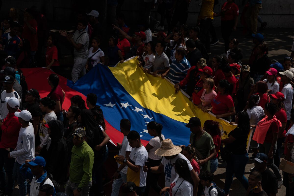 Protesters hold a large Venezuelan flag.