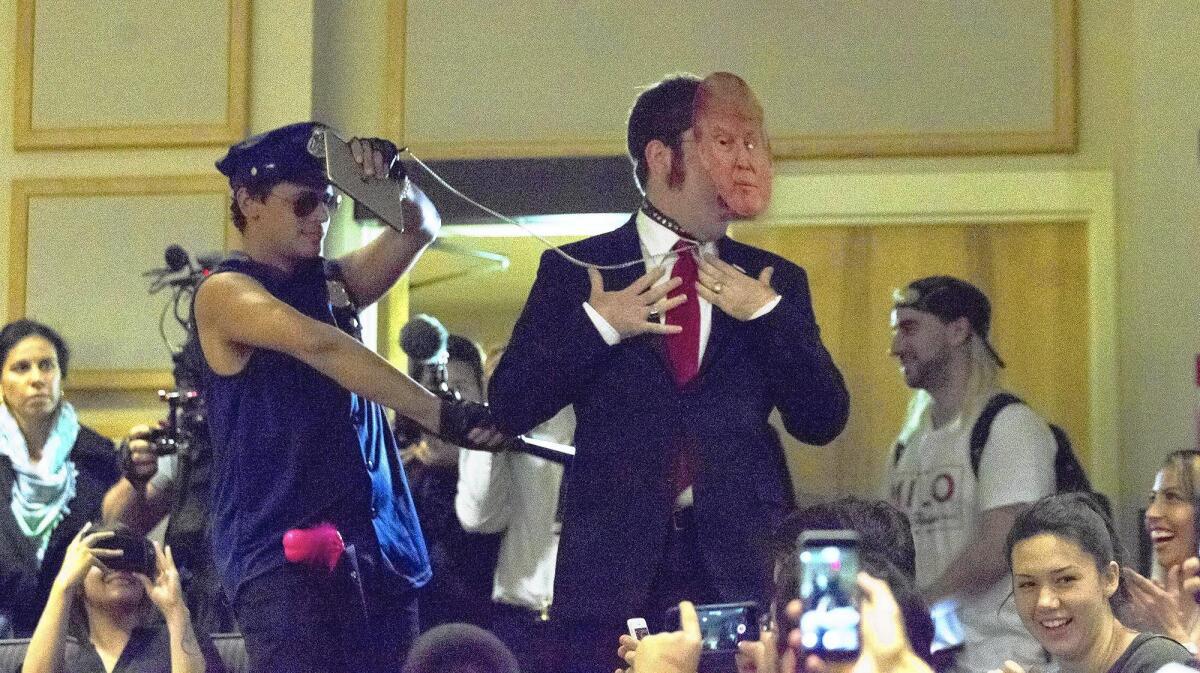 Milo Yiannopoulos, left, an editor for conservative website Breitbart.com, makes his entrance with a man in a Donald Trump mask during an event in June presented by the College Republicans at UC Irvine.