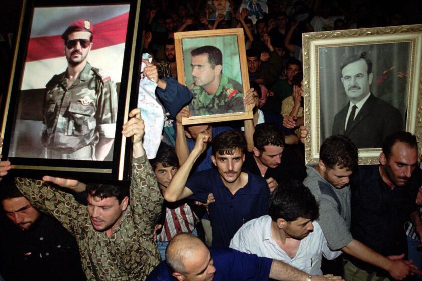 FILE - In this June 10, 2000 file photo, Syrian mourners wave portraits of President Hafez Assad, right, and his two sons Bashar, center, and Basil who died in a car accident in 1994 to mourn the death of their president, in Damascus, Syria. For fifty years, the Assad family has controlled Syria, overseeing transformations, modernization, uprisings and upheaval while becoming among the most divisive figures of their time. (AP Photo/Hussein Malla, File)