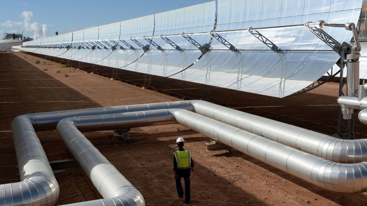 Un trabajador camina delante de los espejos solares en la planta de energía solar concentrada Noor 1 de Marruecos en el borde del Sahara. Los investigadores dicen que el despliegue generalizado de parques solares y eólicos en el desierto africano podría causar que caiga más lluvia y que crezcan más plantas.